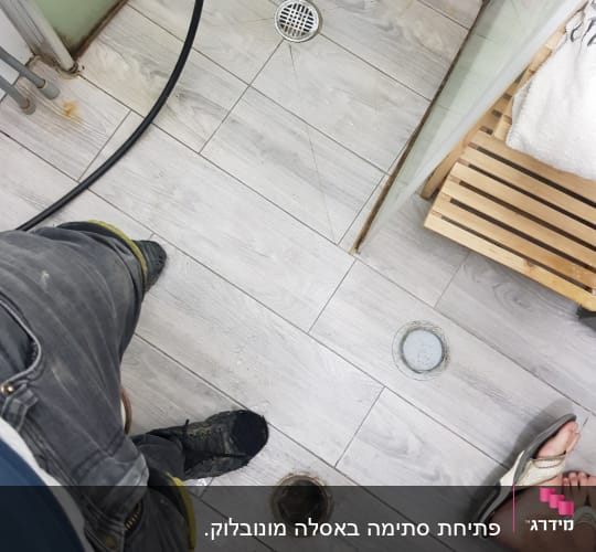 רצפת חדר אמבטיה עם פתח ניקוז פתוח וצינור עבודה
